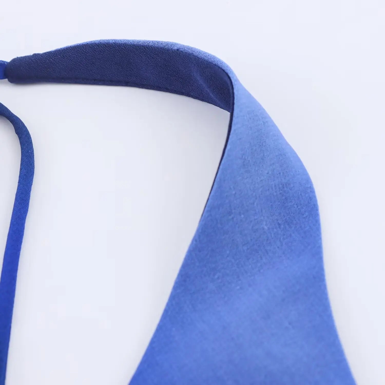Close‑up of halter strap binding workmanship, neat stitching on blue lightweight chiffon fabric
