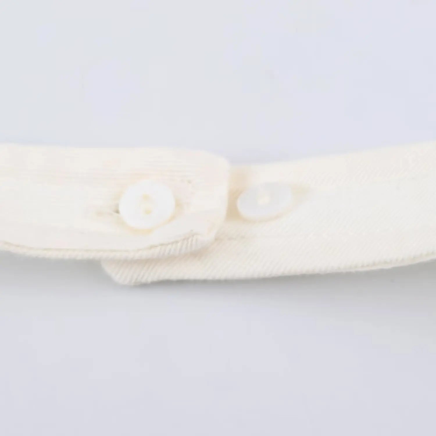 Macro close up of two white matching buttons for adjustable halter neck strap closure