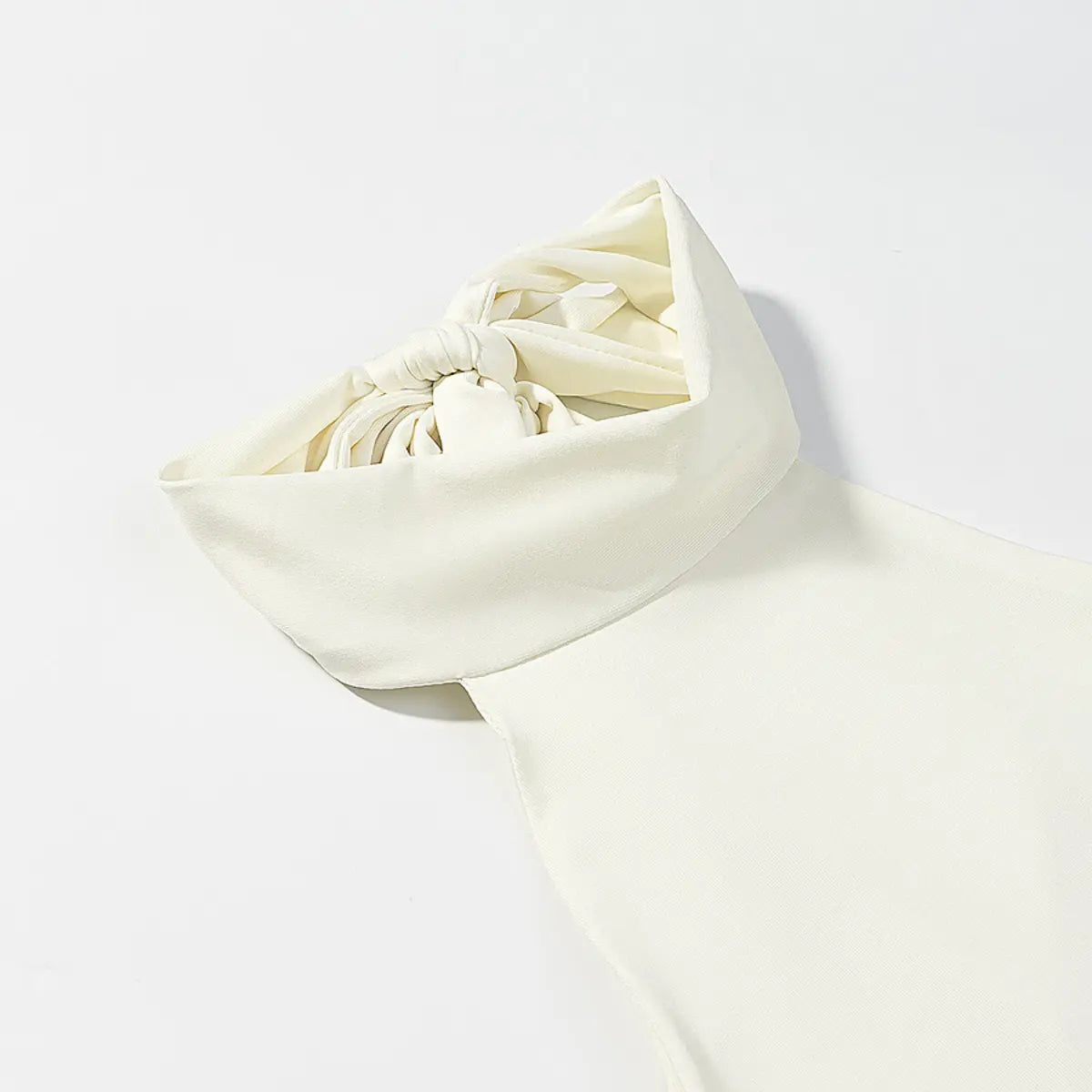  Close-up of the halter neck bow detail on a cream mini dress, showing the structured knot and clean stitching.