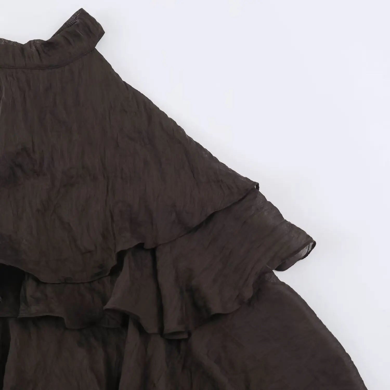 Close-up of waterfall ruffle trim on dark brown halter mini dress, crinkled lightweight woven material layered stitching