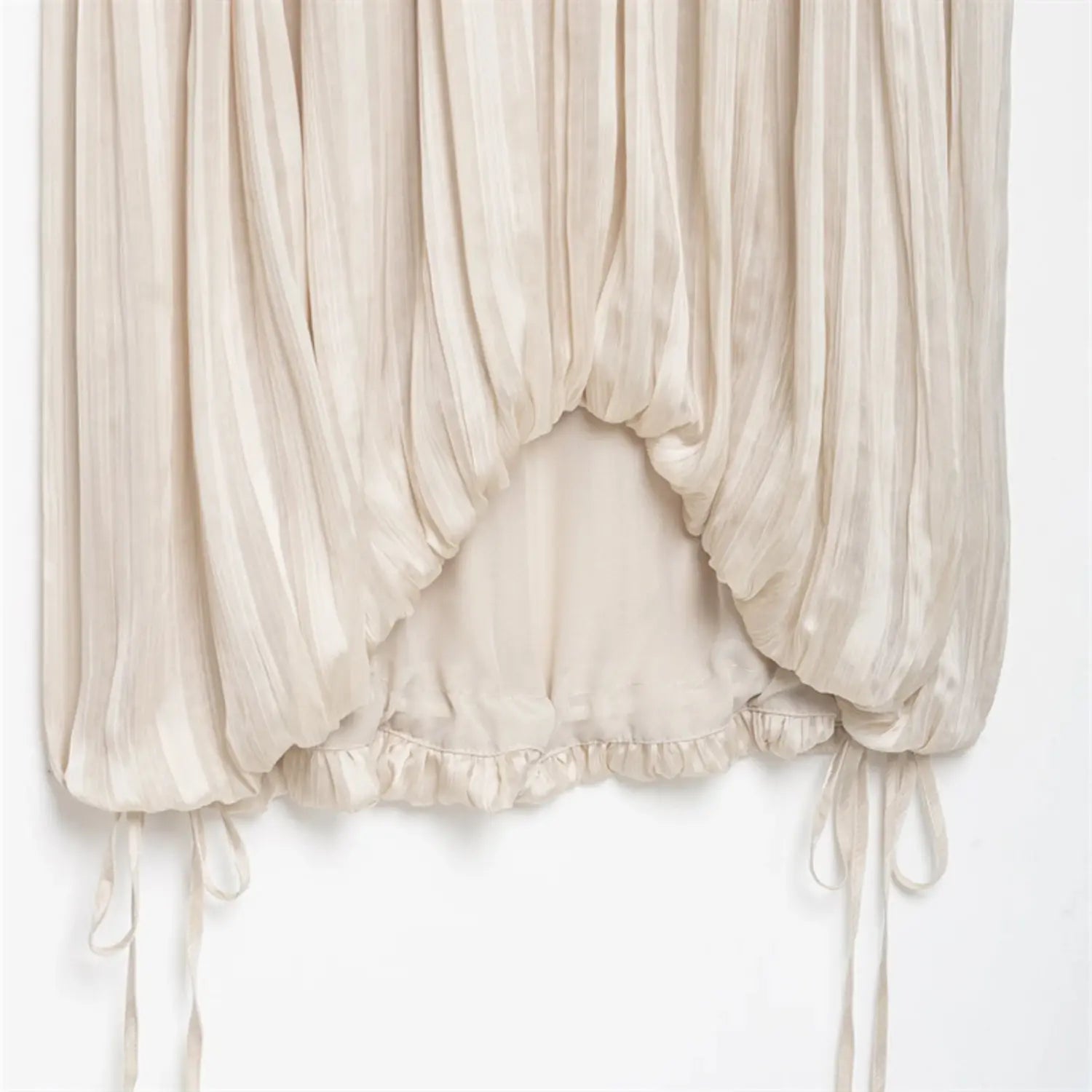 Bottom full shot, symmetrical side drawstrings, ruched bubble hem with ruffled inner lining edge