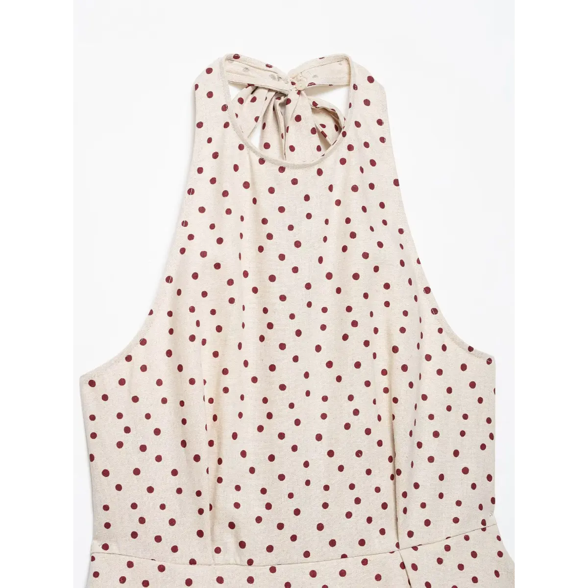  Close-up of the halter neckline on a beige red polka-dot top, showing the scoop front and sleeveless design.