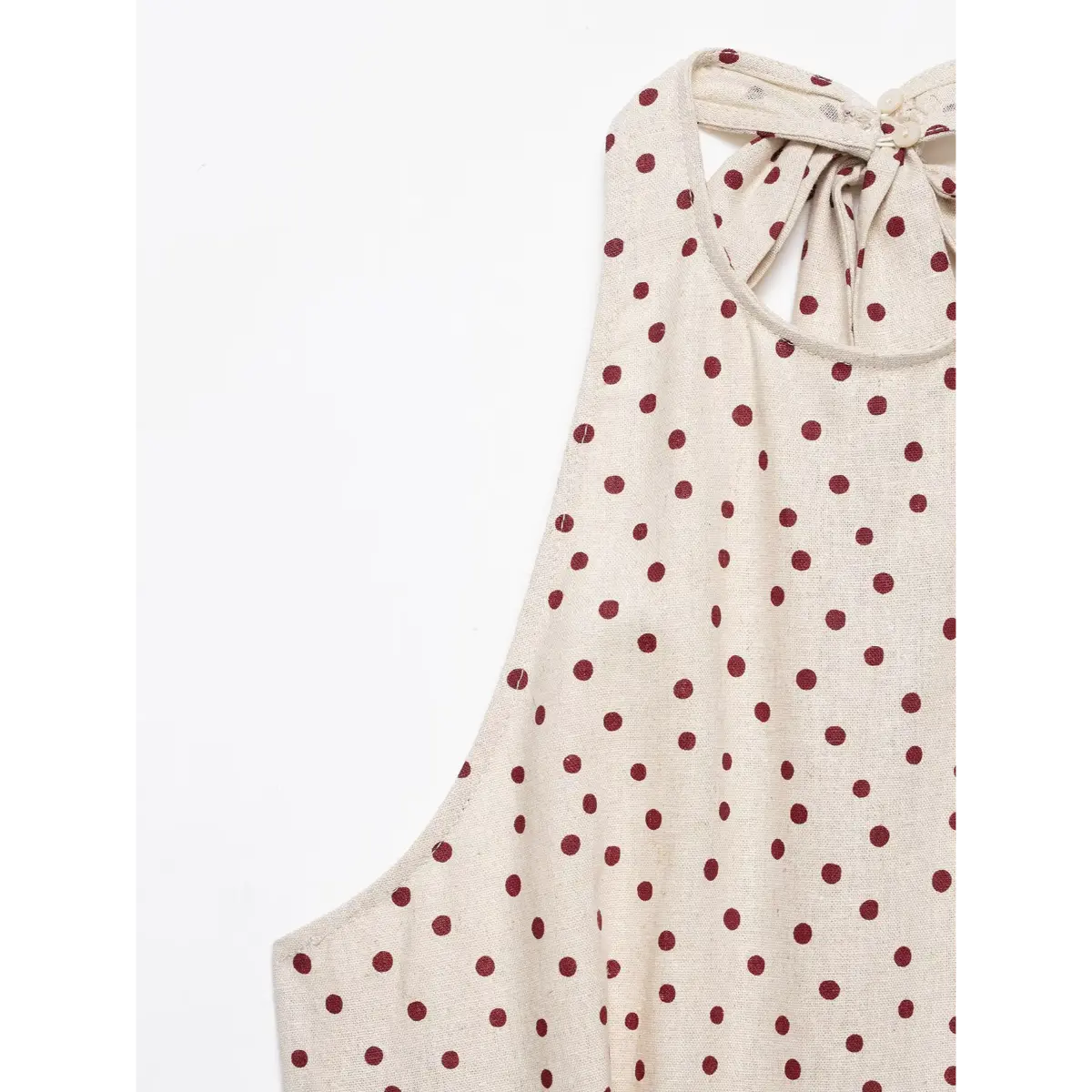 Close-up of the halter neckline on a beige polka-dot top, showing the tie closure and buttons at the back.