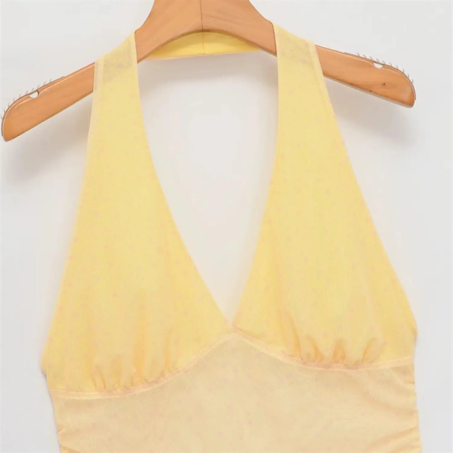 Hanger close-up of halter neckline, deep V front, gathered bust seam, sheer pale yellow dot mesh overlay, soft stretch lining