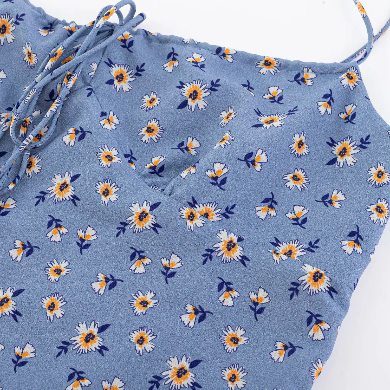 Haze blue base white yellow daisy chiffon fabric macro shot, fresh small flower print drape woven fabric wrinkled flat lay detail