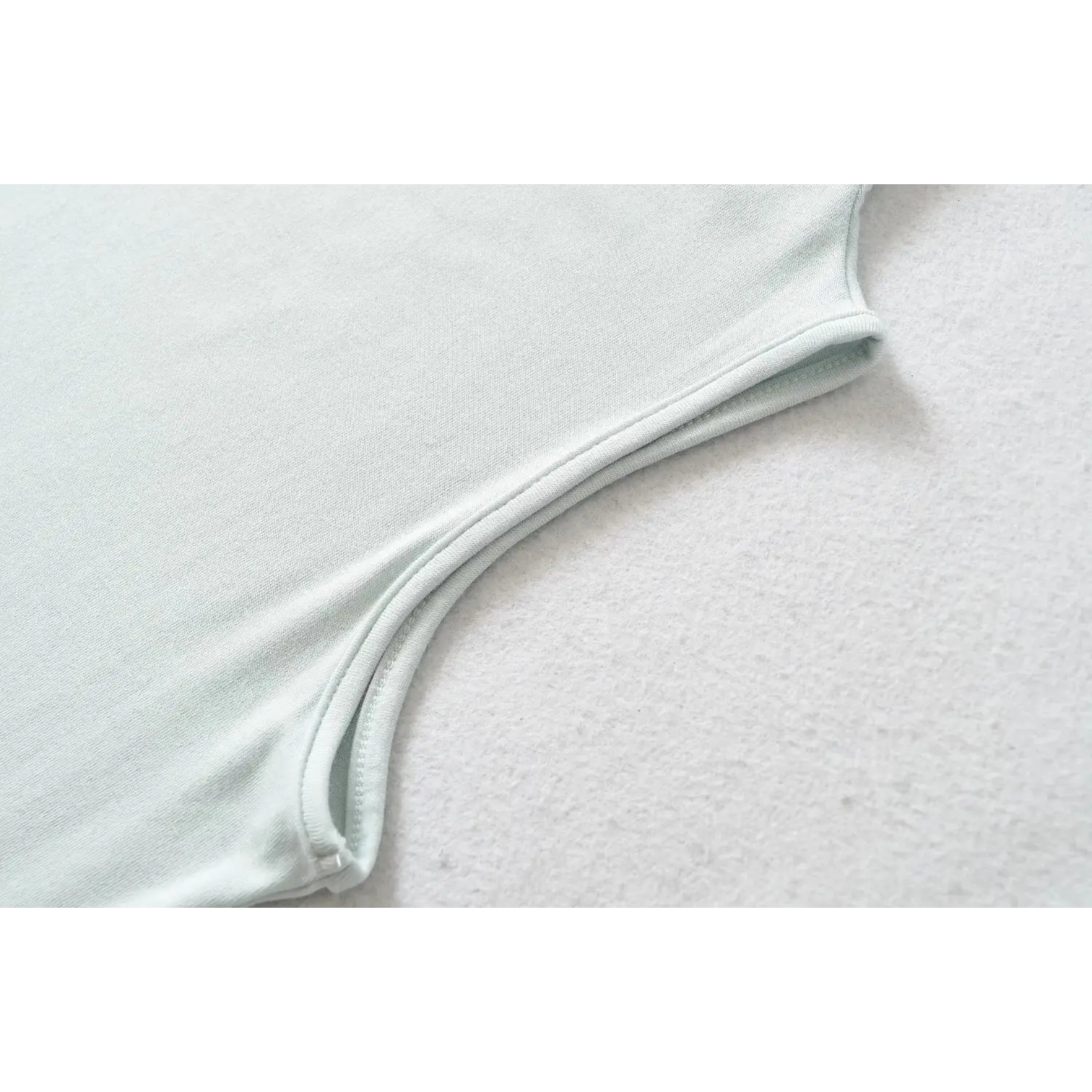 Close-up of armhole stitching detail on haze blue high neck sleeveless skater dress, neat finished seam