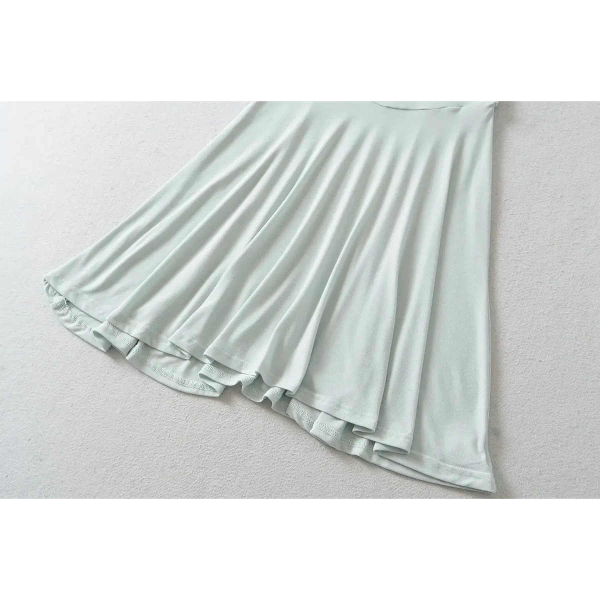 Close up detail of haze blue skater dress flared skirt hem, soft draped fabric