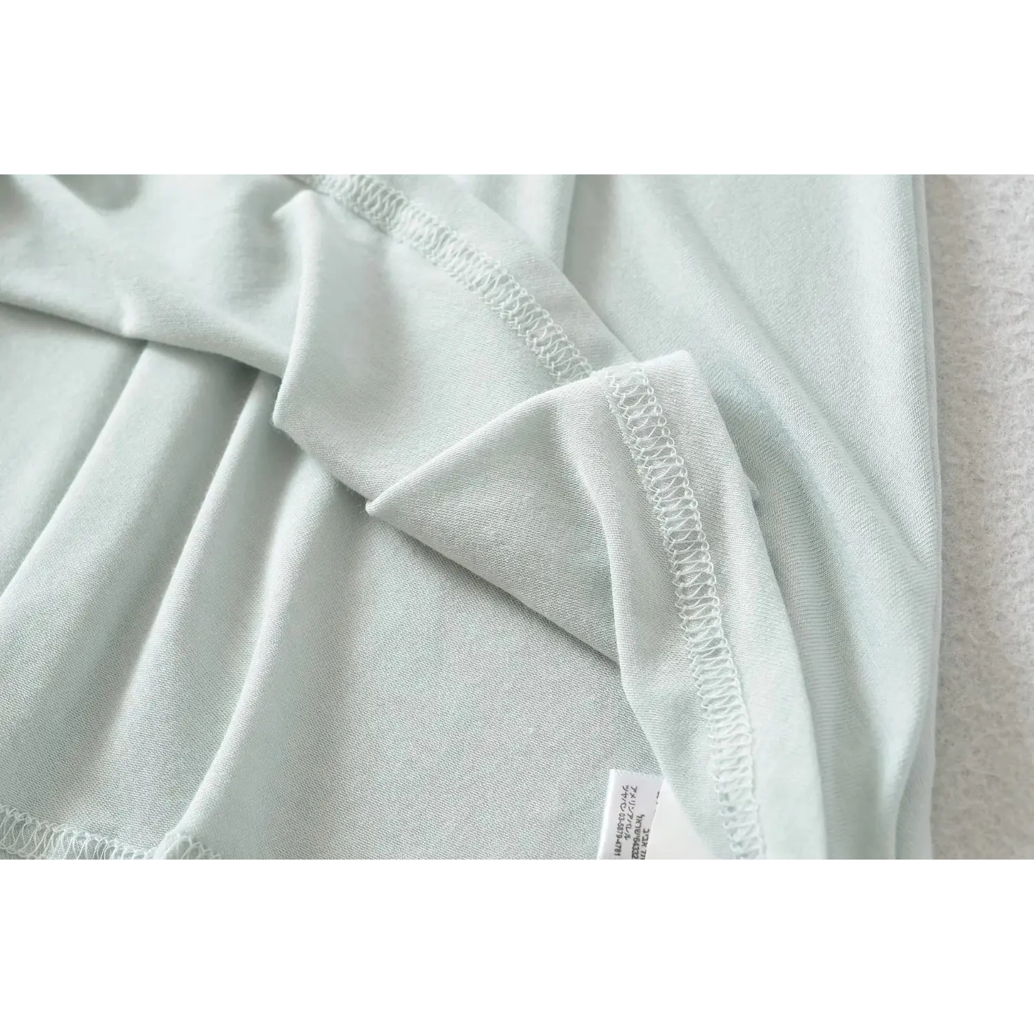 Close-up of inner serged seam and clothing label on haze blue high neck sleeveless dress