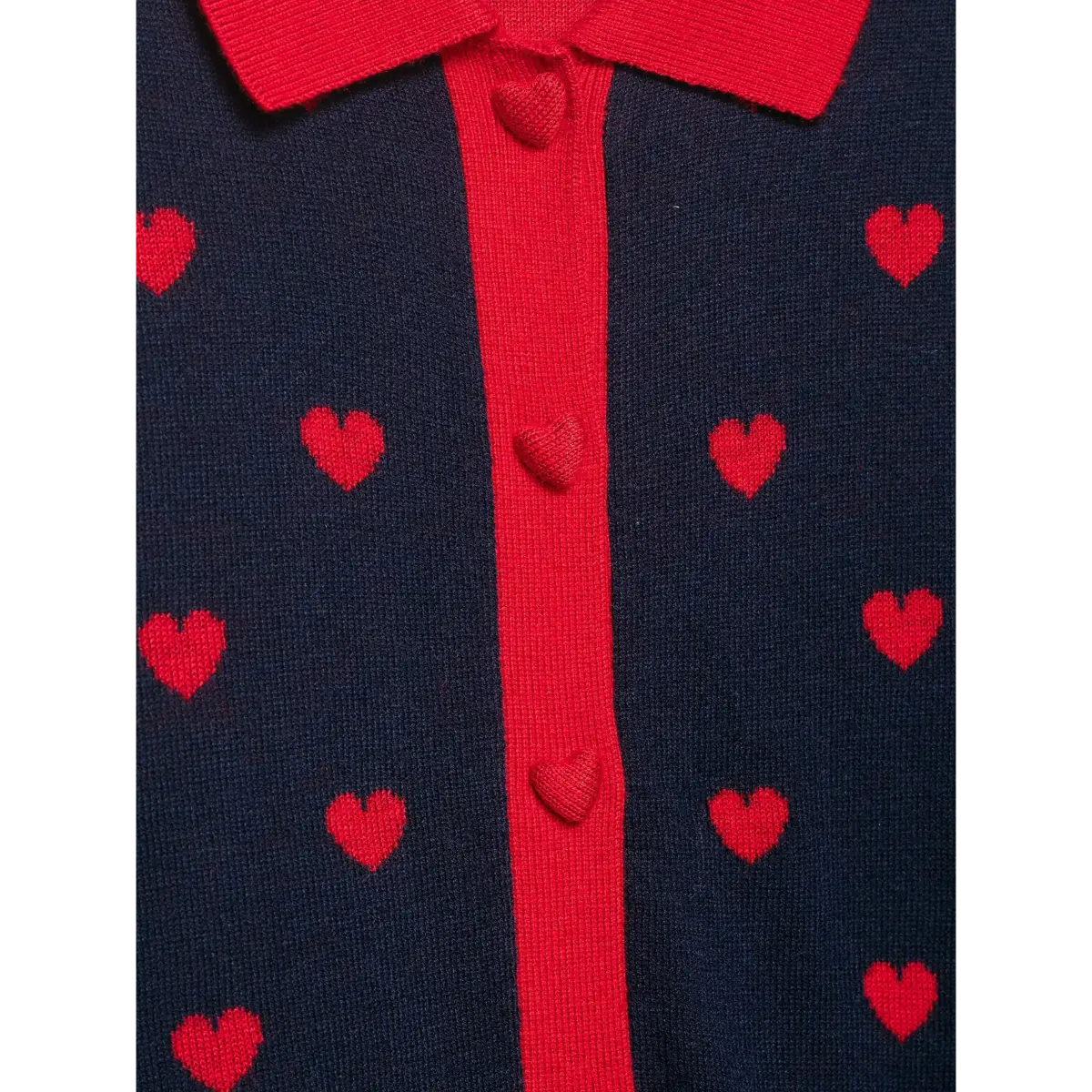 Close-up of the heart-shaped red buttons on a navy and red heart-patterned knit cardigan.
