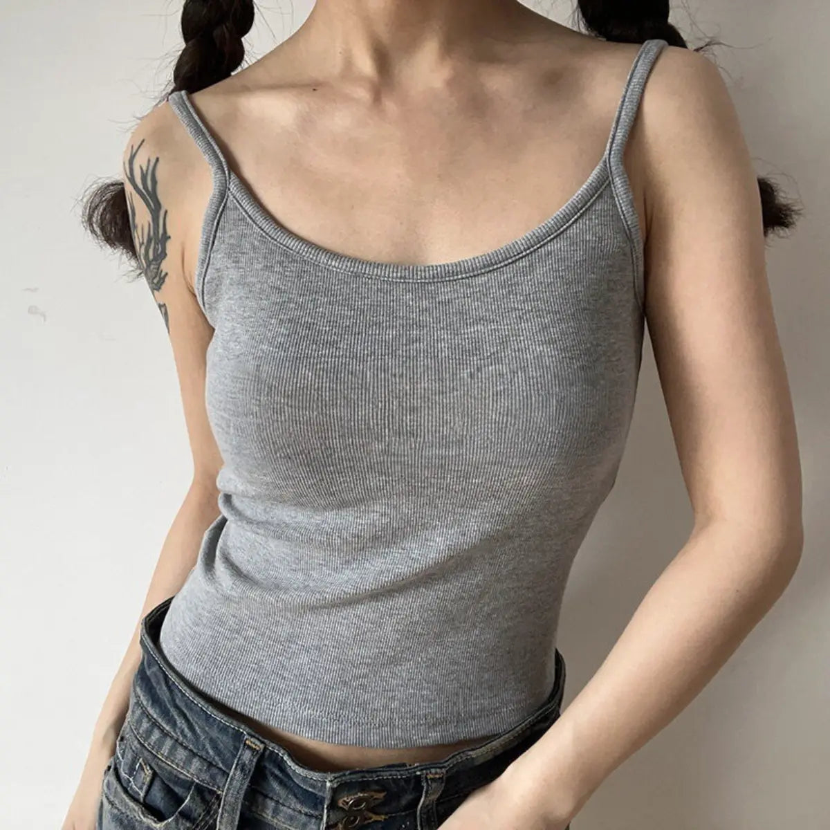 Lifestyle shot of form-fitting heather gray ribbed camisole with thin straps, tucked into jeans