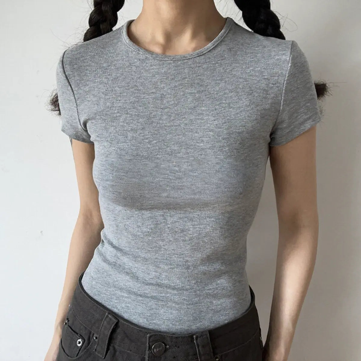 Lifestyle shot of form-fitting heather gray ribbed crew-neck short-sleeve t-shirt, tucked into jeans
