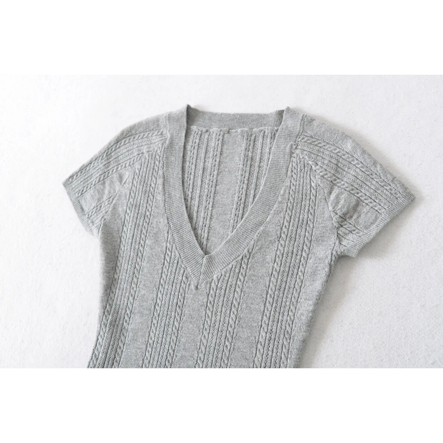 Close up flat shot of heather gray deep v cable knit top neckline & chest vertical twist knit texture