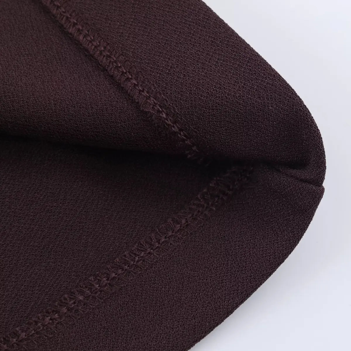 Close-up of the hem and seam construction on a brown V-neck cap sleeve dress, highlighting the clean, reinforced stitching.