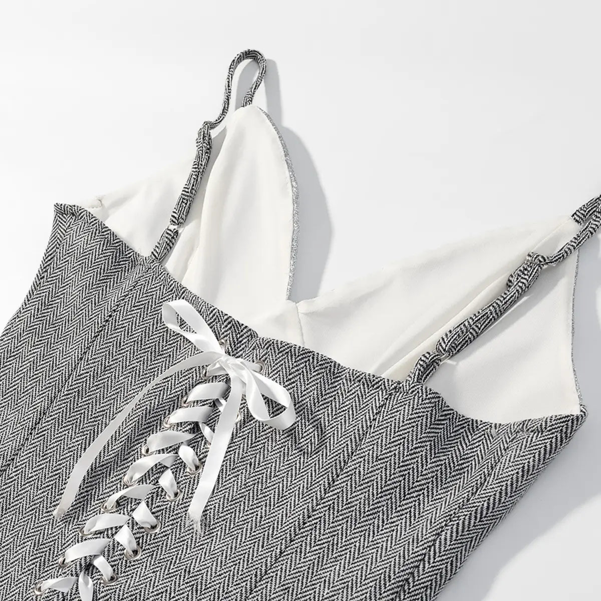 Close-up of the strap and lace-up detail on the herringbone cami top, featuring the matching woven strap, silver eyelets, and white ribbon tie
