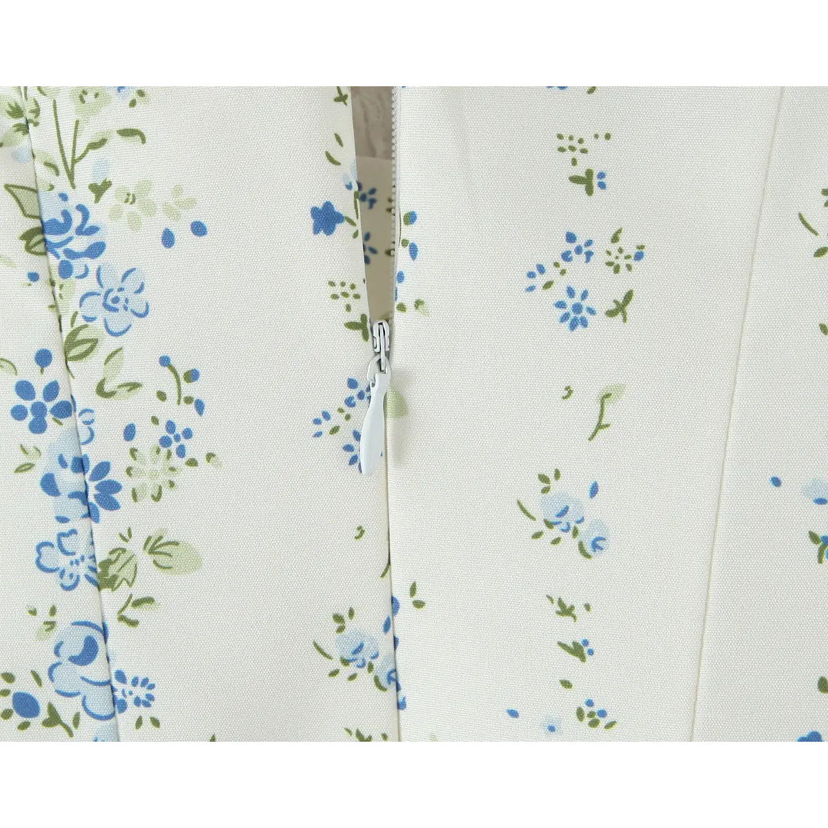 Close-up of the hidden side zipper on a cream floral dress, showing the fabric-covered pull and matching print.