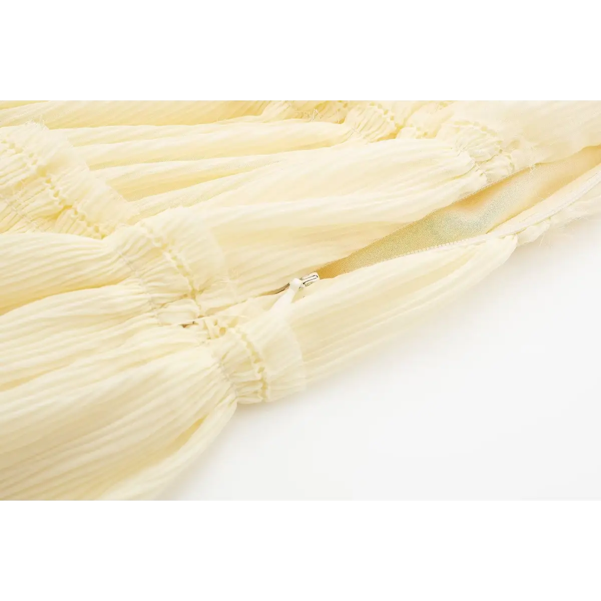 Close-up of the hidden side zipper on a cream smocked cami dress, showing the fabric-covered pull and seamless integration.