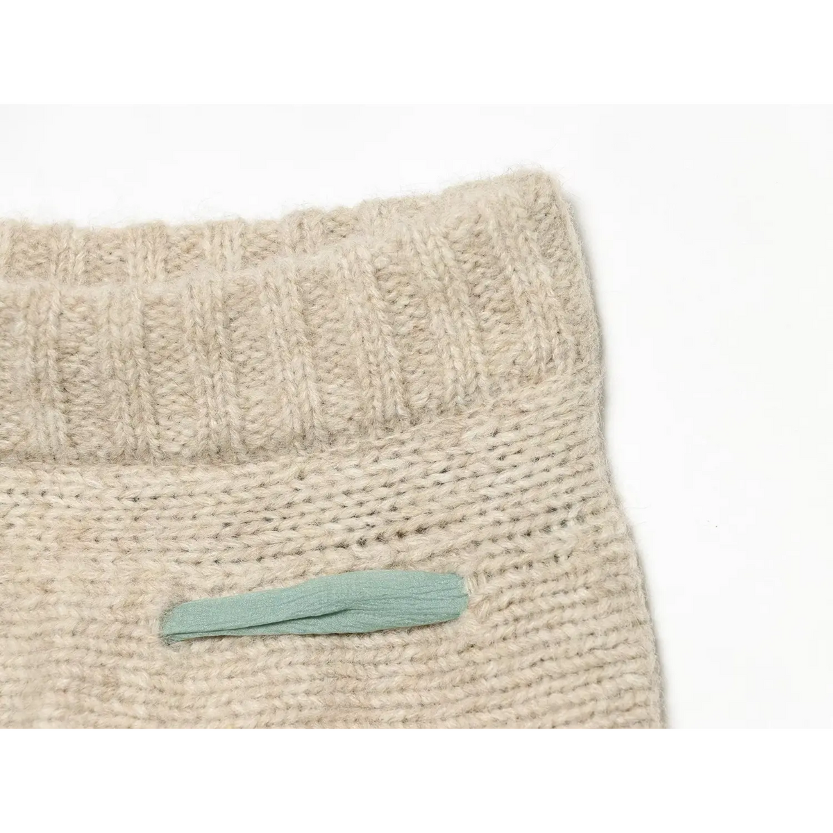 Close-up of ribbed high waistband and mint ribbon pocket trim on oat cable knit skort
