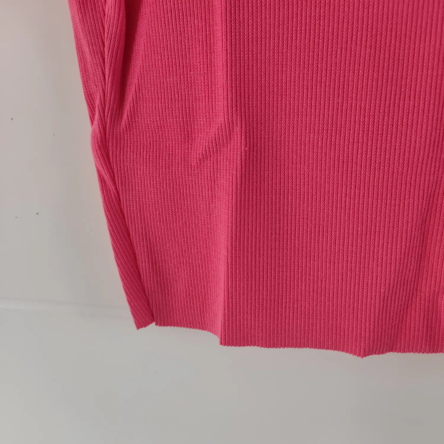 Close‑up raw cut bottom hem fabric texture hot pink ribbed crop top