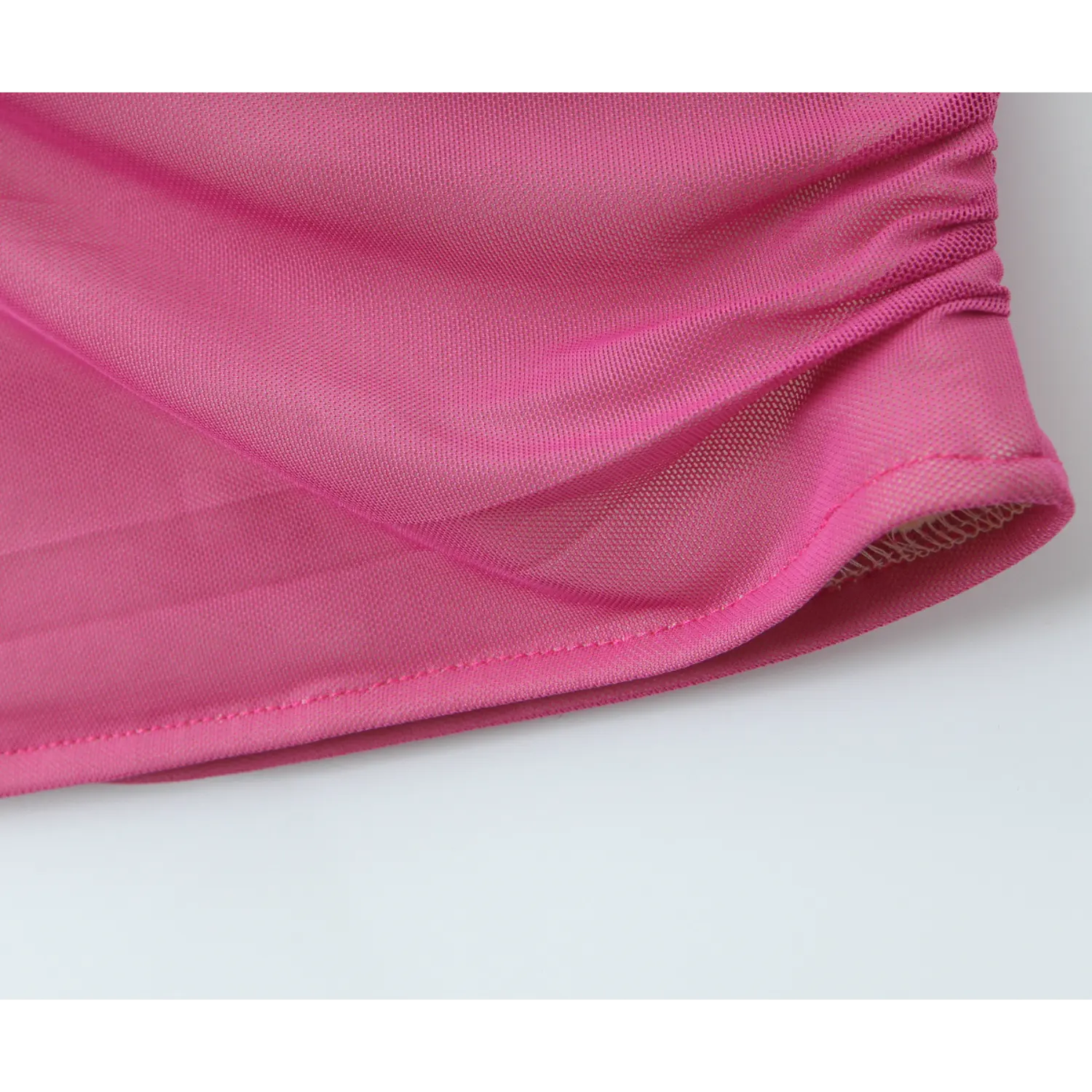 Close‑up of dress bottom hem, finished stitching and soft hot pink mesh fabric texture