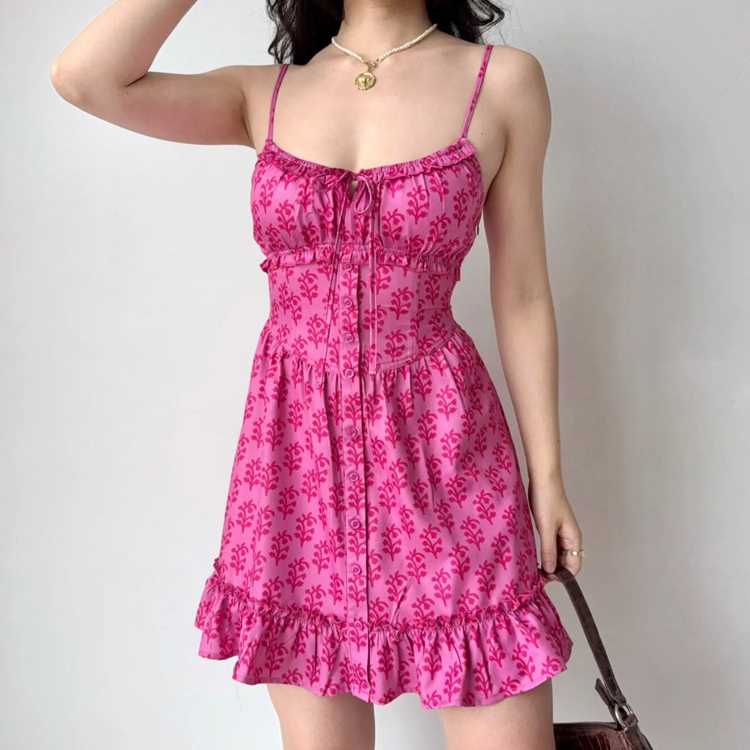 Model front one arm up pose hot pink plant print corset waist cami mini dress tie bust front button ruffle hem sundress