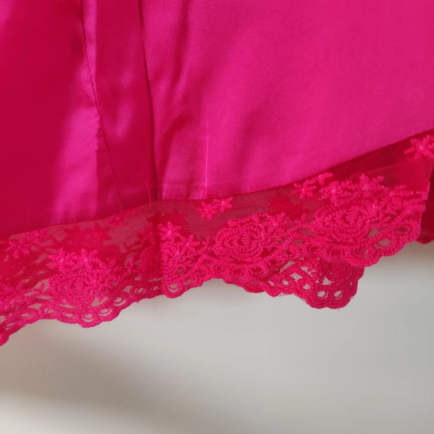 Close‑up bottom hem floral lace trim and glossy satin fabric texture