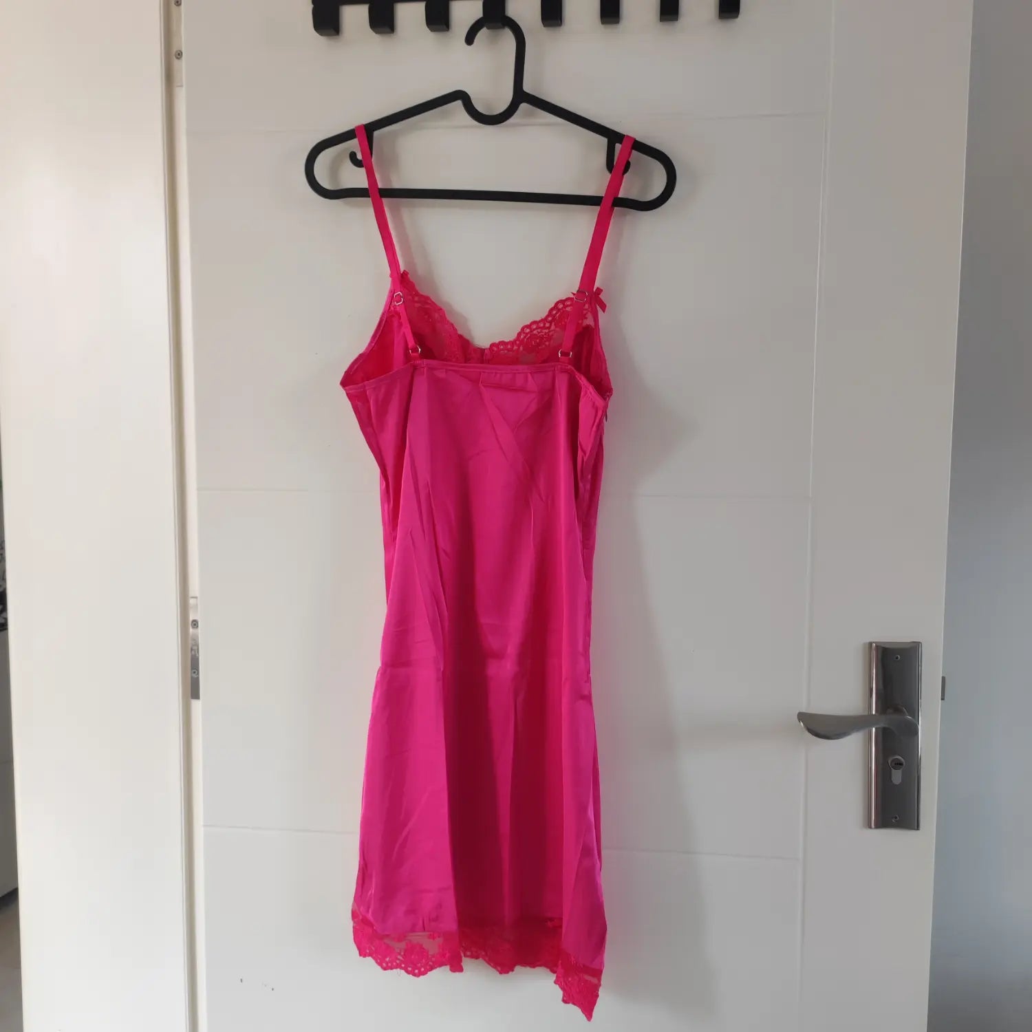Back hanging view hot pink satin slip mini dress with adjustable spaghetti straps and lace trim
