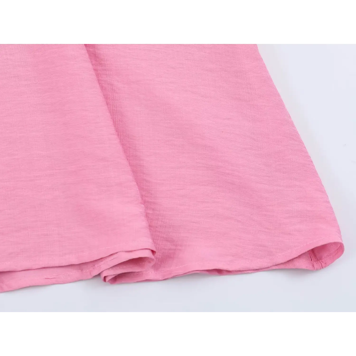 Bottom hem closeup, neat folded finished seam on textured pink fabric
