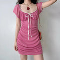 Female model wearing hot pink square neck ruched mesh bodycon mini dress, white lace trim and front tie bow, short puff sleeve