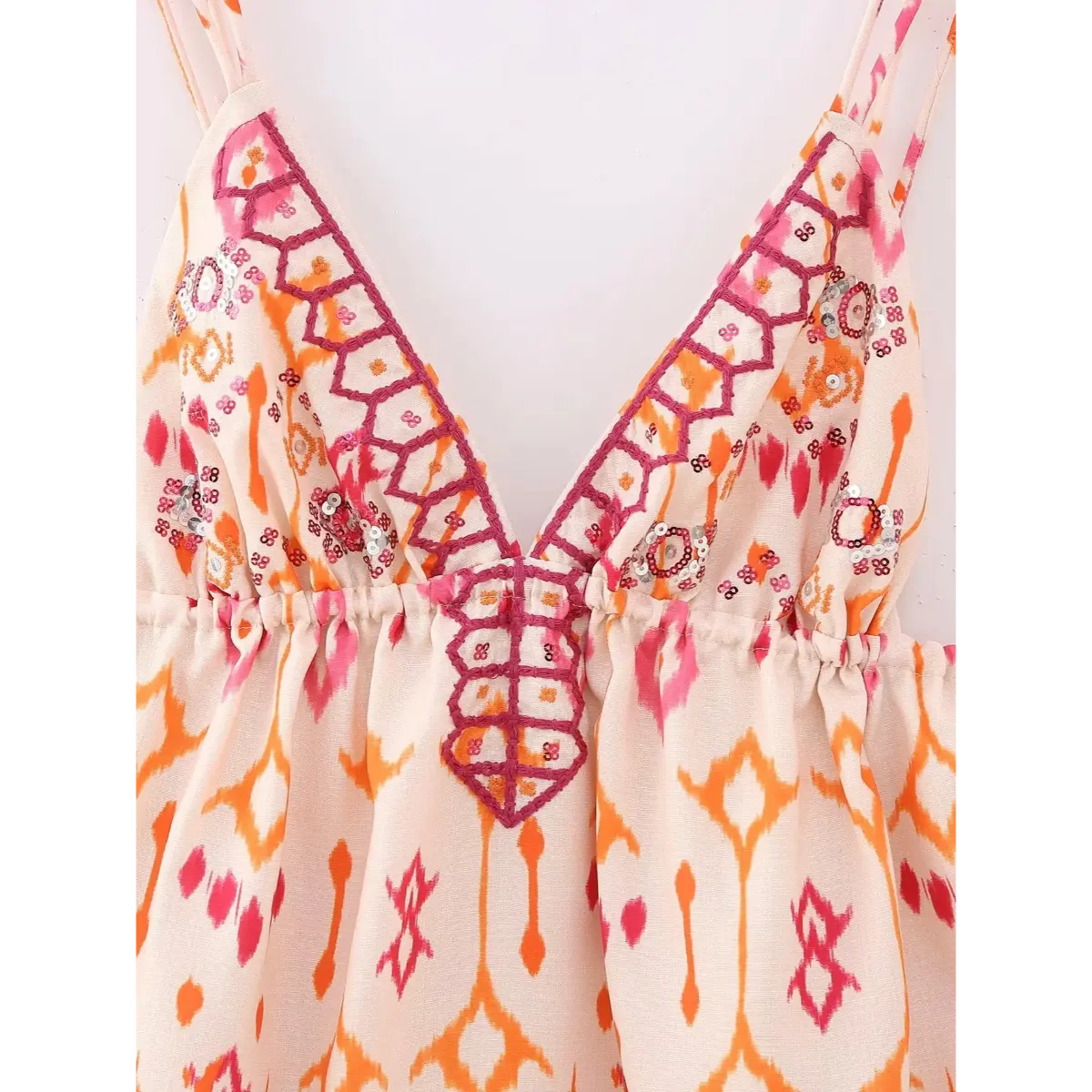 Full view of the ikat print cami top, showing the V-neckline, gathered bust, double spaghetti straps, and pink/orange ikat pattern
