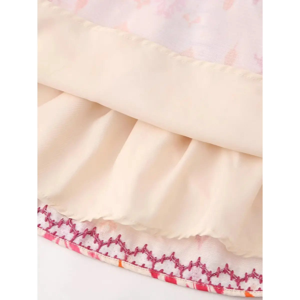 Close-up of the lining on the ikat print cami top, showing the ruffled hem and pink embroidery on the outer layer
