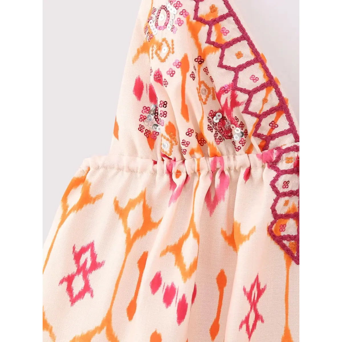 Close-up of the side gathered seam on the ikat print cami top, showing the ikat pattern and pink embroidery