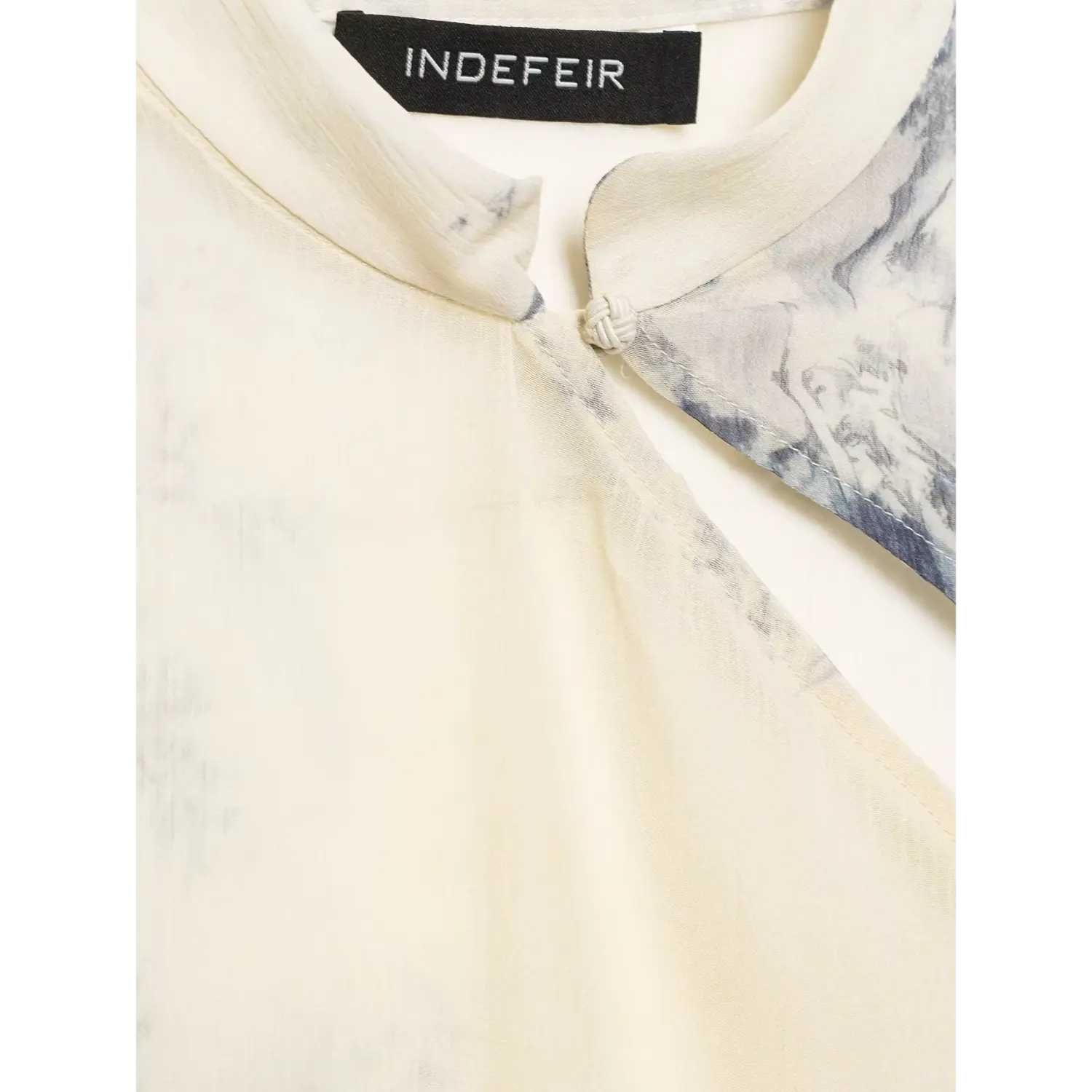 Neck inner tag macro shot, black woven label printed brand text INDEFEIR, mandarin collar inner lining