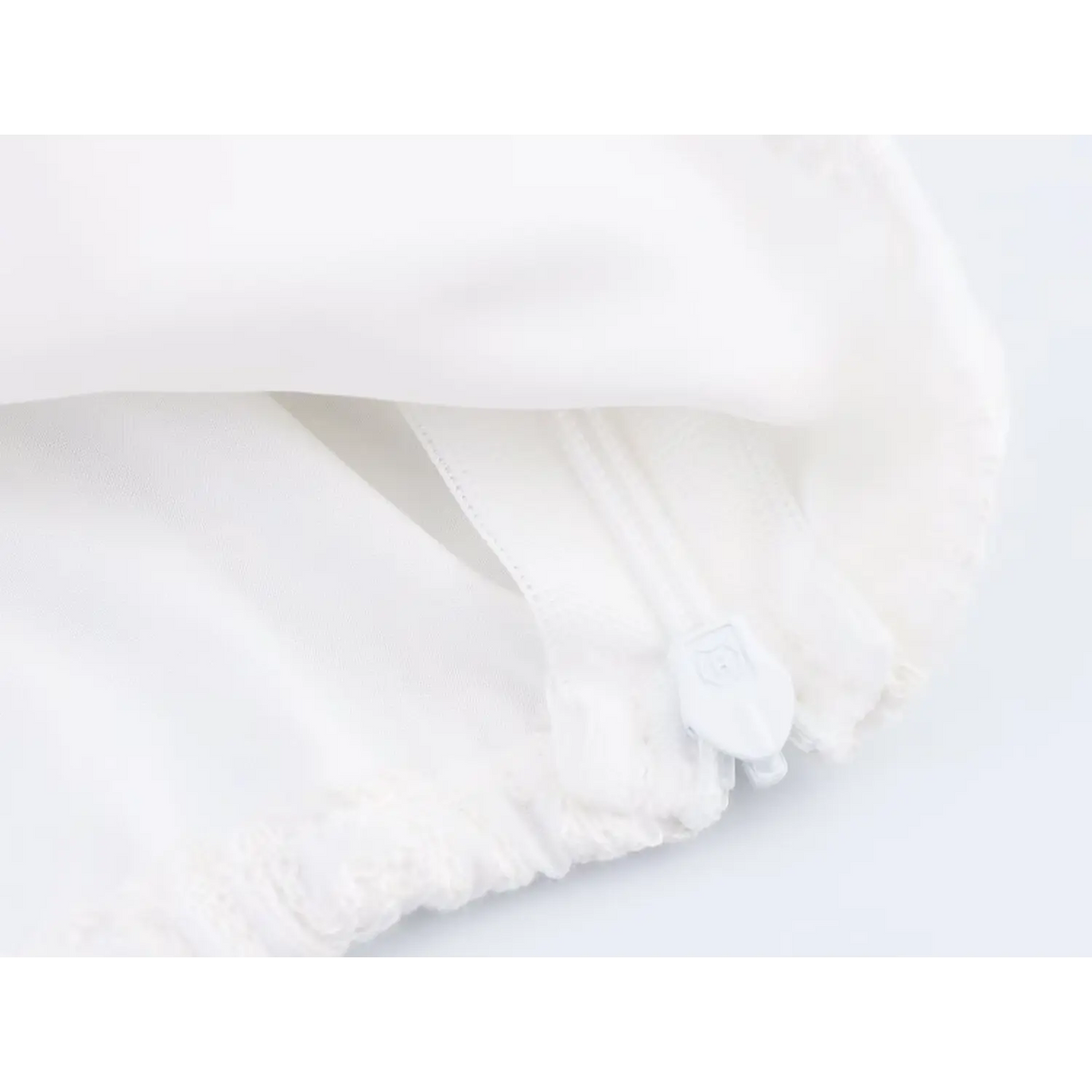 Inside shot of white invisible zipper with zipper pull on embroidered crop blouse