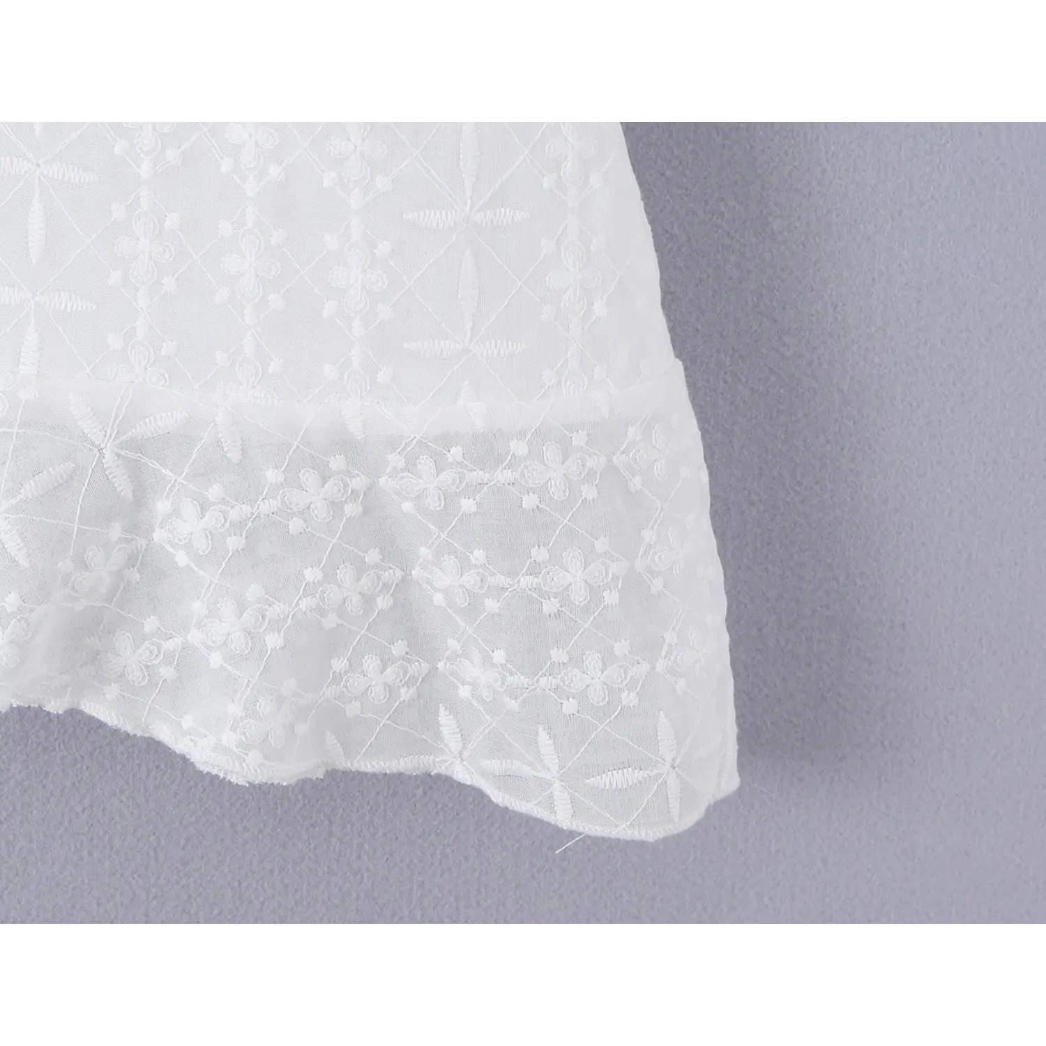 Irregular wavy ruffle hem eyelet lace seam macro close-up, layered flutter binding neat serging flowy A-line mini skirt hem craft shot