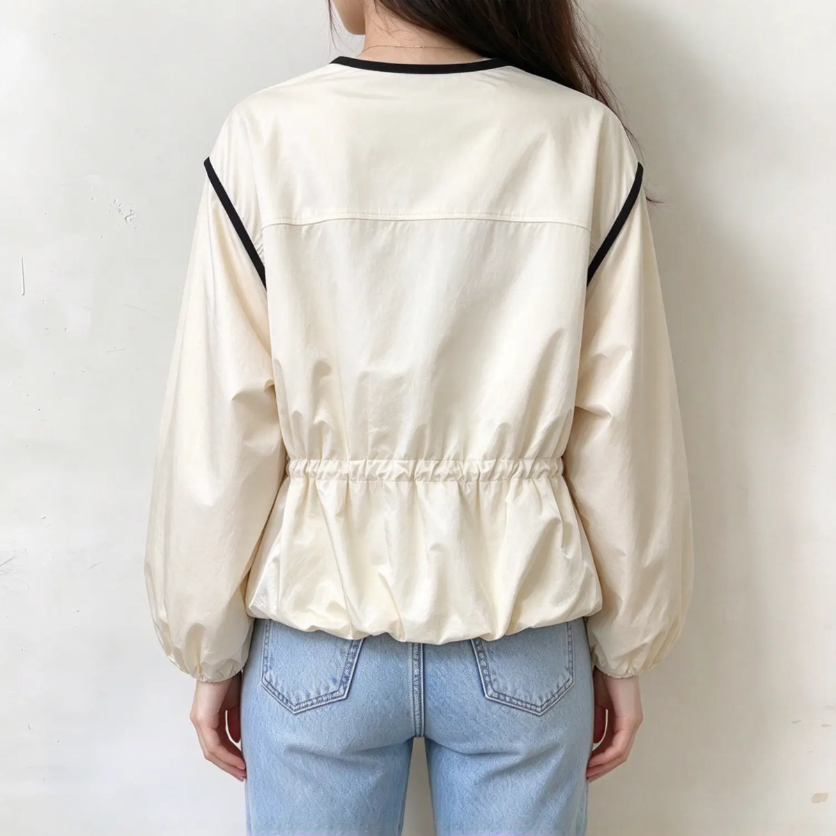 Model wearing ivory black trim crew neck gathered waist puff sleeve jacket