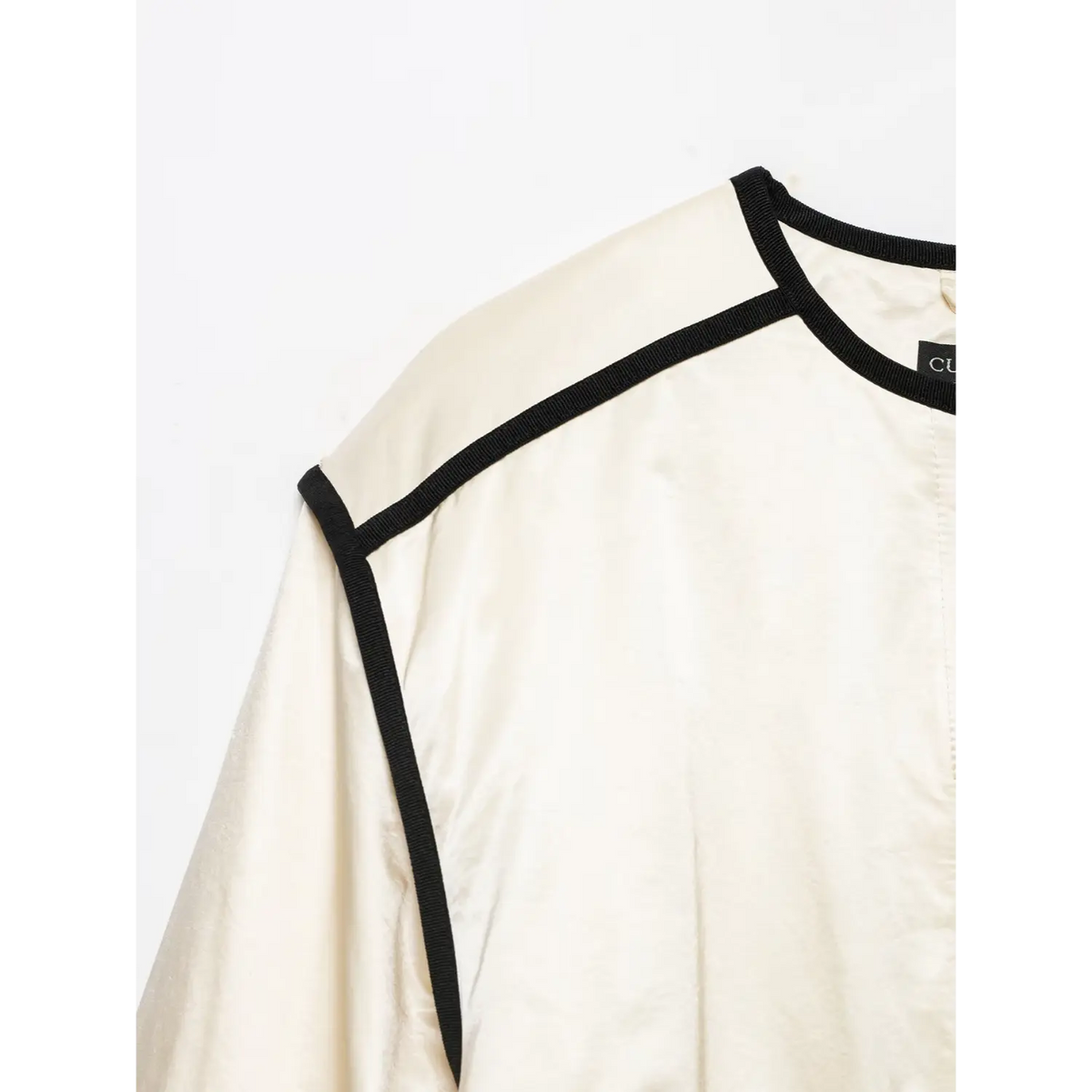 Close-up of shoulder black piping trim and crew neckline