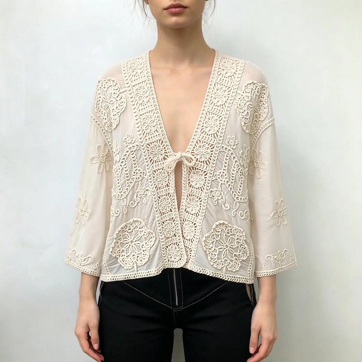 Model wearing ivory crochet lace cropped jacket with black jeans