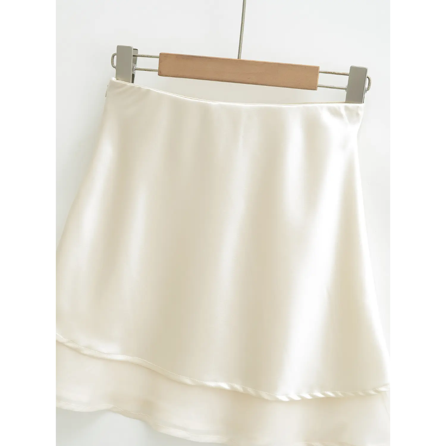 Ivory double layer satin mini skirt full wooden hanger shot, smooth high waistband staggered double mesh hem soft glossy satin A-line swing full silhouette shot