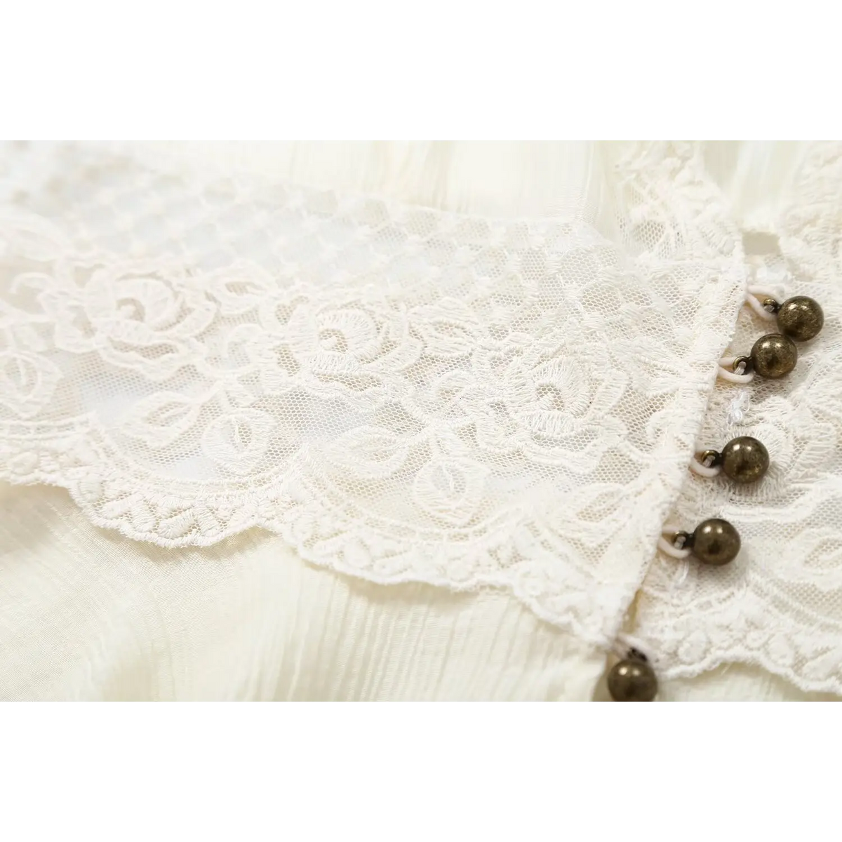 Close-up of floral lace and metal bead buttons