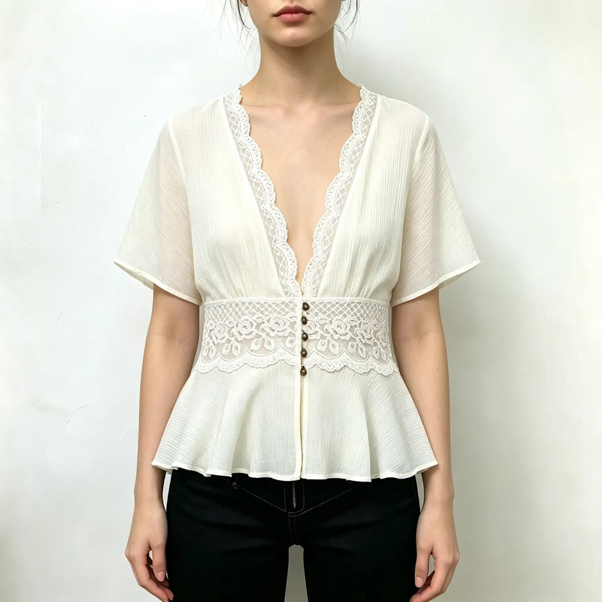 Model wearing ivory lace trimmed V neck peplum top with black trousers