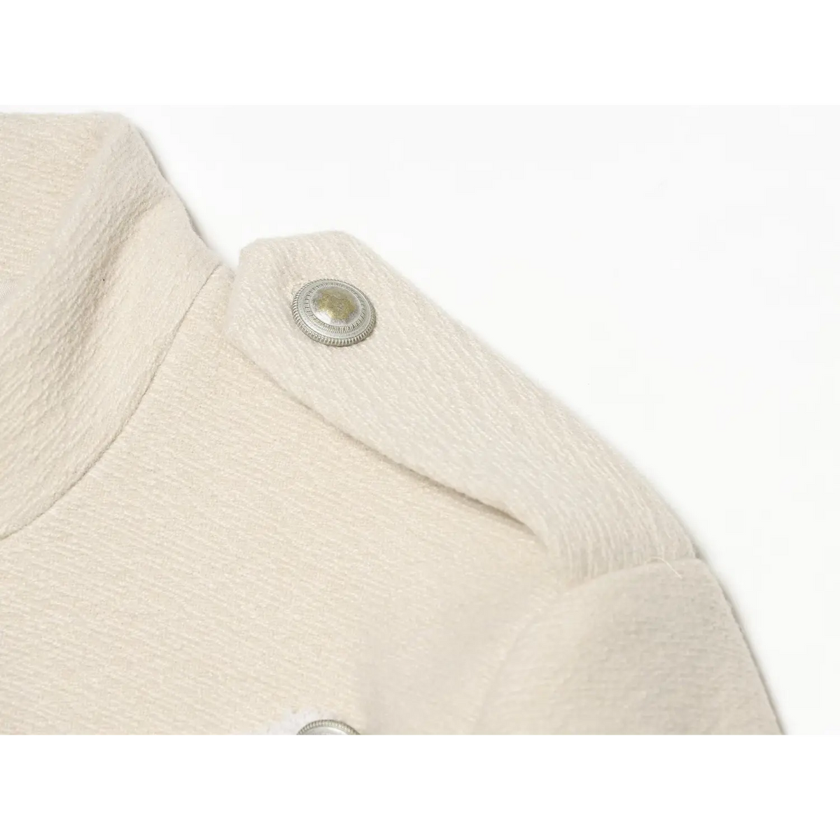 Close-up of shoulder epaulette and metal button on ivory military jacket
