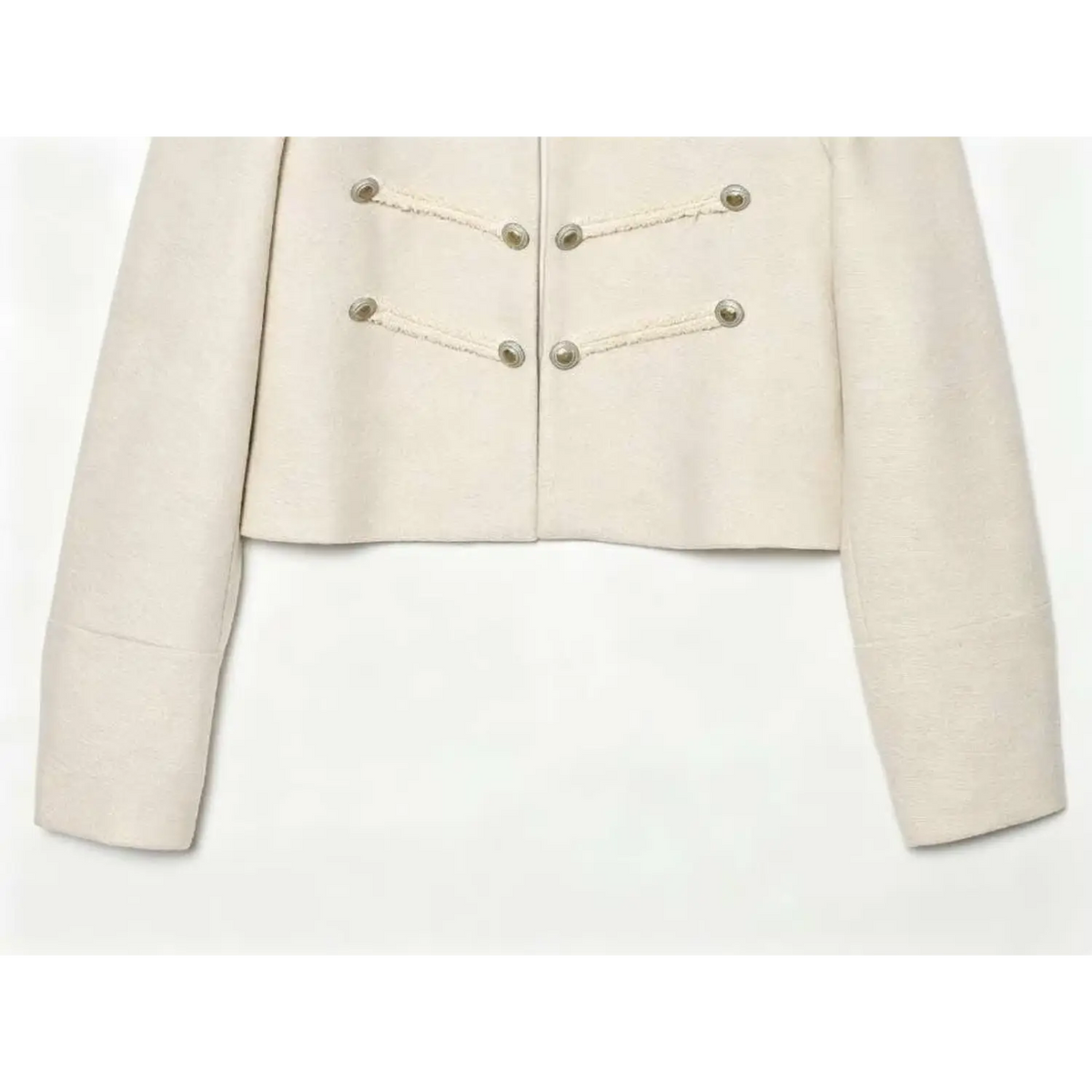 Close-up of cropped hem and button cuffs on ivory military jacket