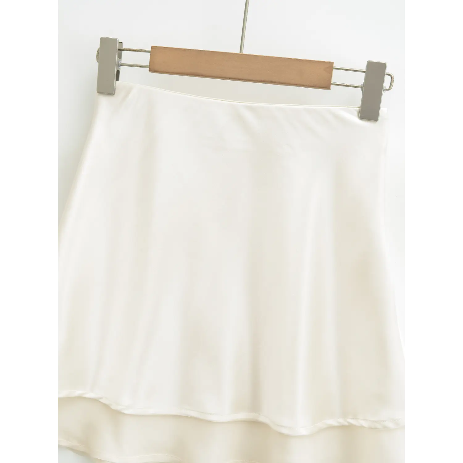 Clean front hanging shot of ivory satin mini skirt, minimal plain high waist A-line silhouette flared double hem soft solid color skirt shot