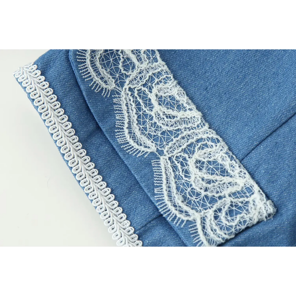 Macro shot of sleeve cuff, white eyelash lace and braided edge trim on blue military style jacket