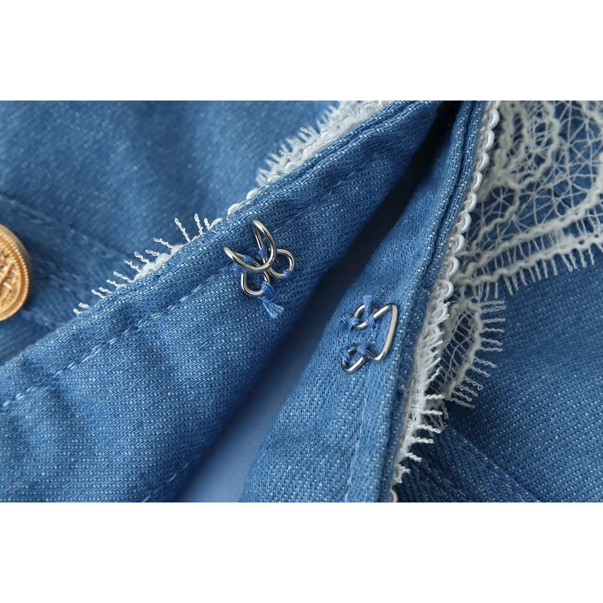 Macro closeup of silver hook and eye clasp on blue lace trim military jacket, inner closure detail