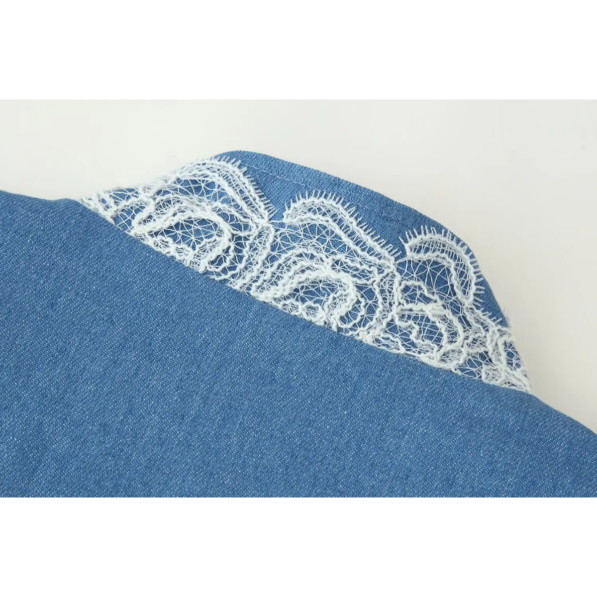 Close-up view of stand collar with intricate white eyelash lace on blue denim look cropped jacket