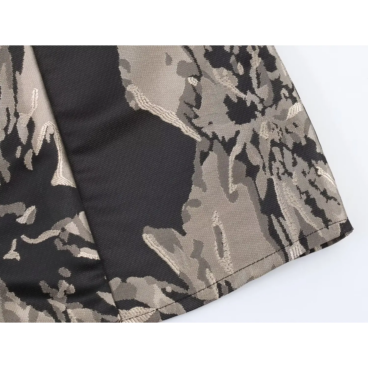 Extreme close-up of woven jacquard fabric texture at skirt hem, black and taupe abstract floral print