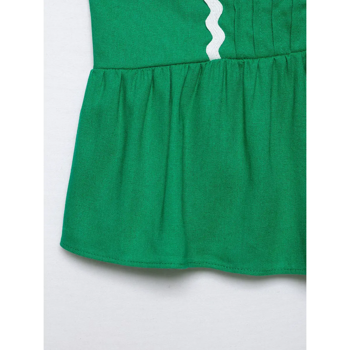 Close of front vertical pleat & white wavy ricrac trim on green cropped cami