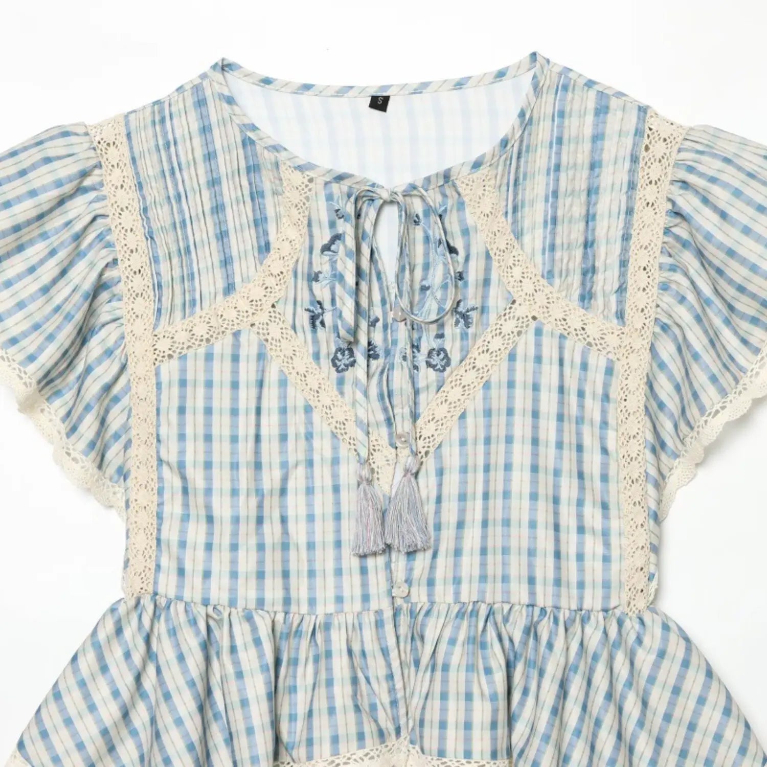 Close-up of round neck keyhole cutout, self tie with gray tassels, blue floral embroidery and geometric hollow lace insets
