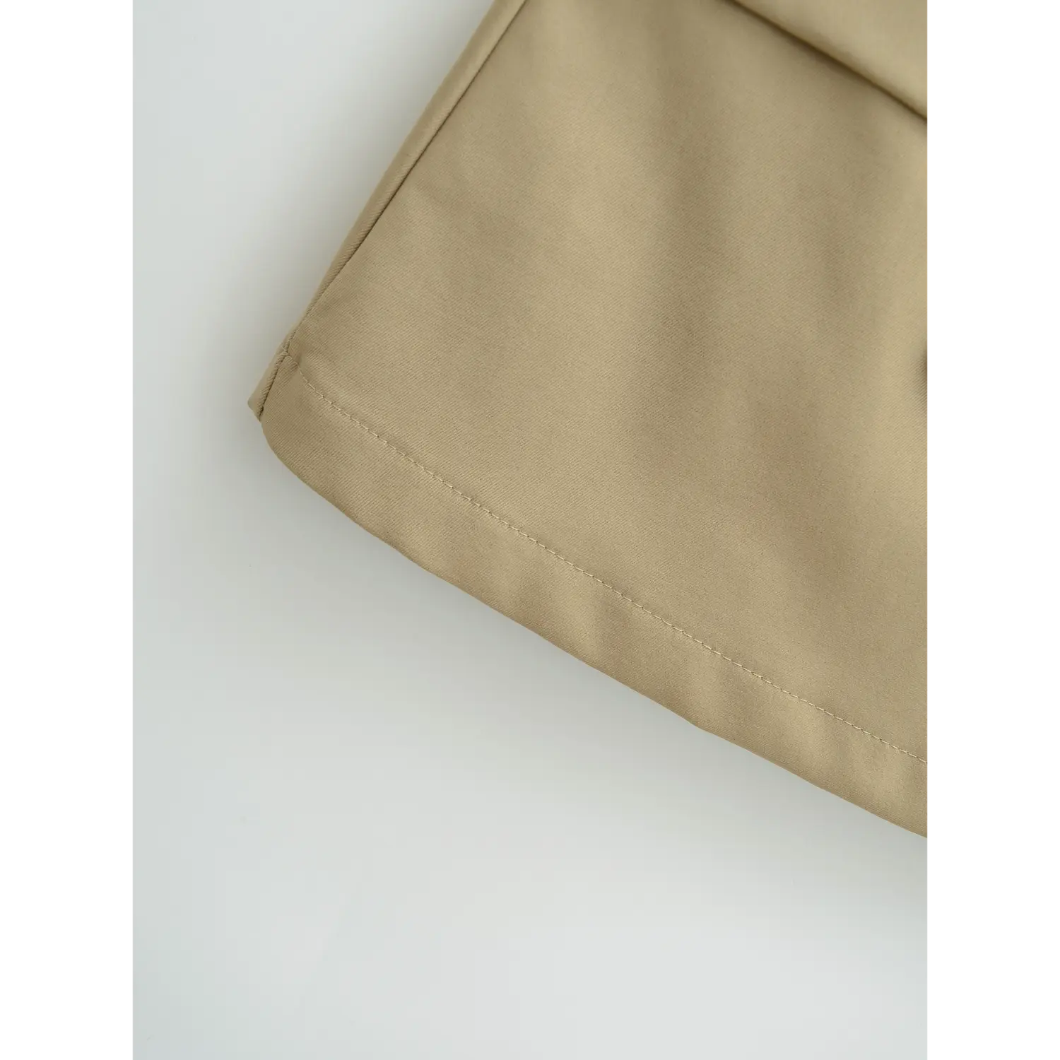 Khaki a-line mini skirt hem flat close-up, even double line overlock binding flared slight a cut stiff wrinkle-resistant twill fabric white background shot